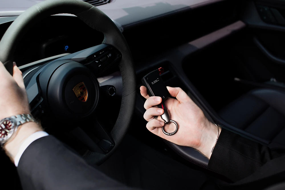 Hand holding Andatech GT Fuel Cell Breathalyser in luxury car