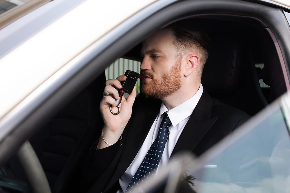 Man blowing into Andatech GT Fuel Cell Breathalyser in car