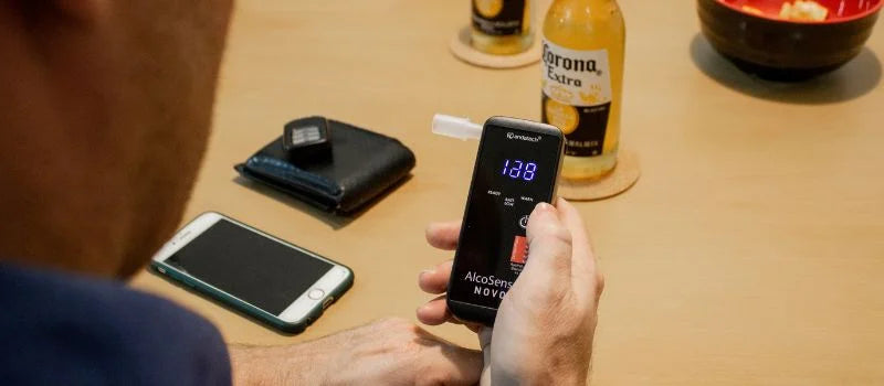 A man holding Andatech AlcoSense Novo personal breathalyser