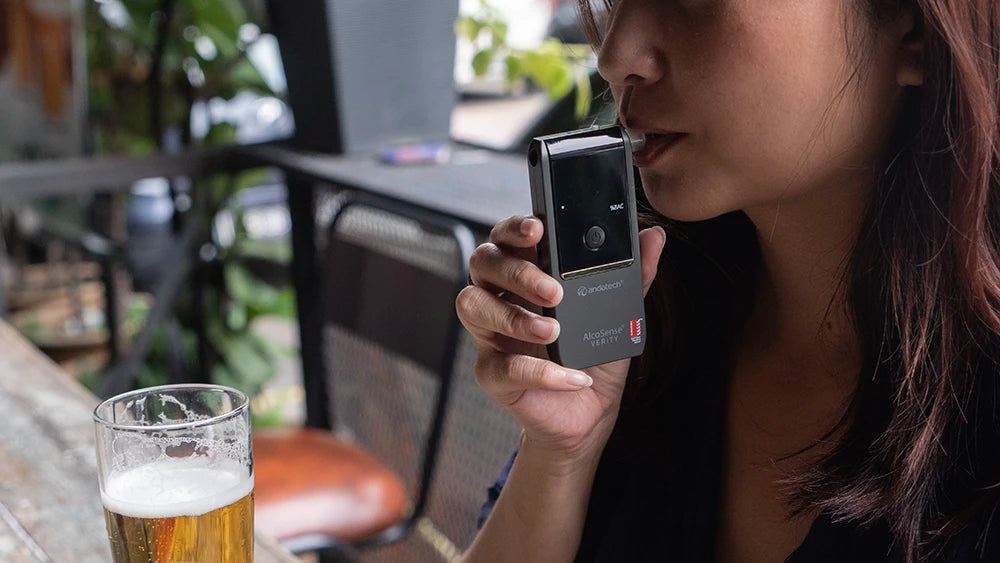 A woman blowing into the Andatech AlcoSense Verity personal breathalyser