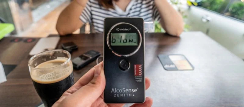 A man holding an Andatech AlcoSense Zenith+ personal breathalyser