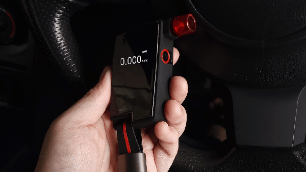 Hand holding Andatech GT Fuel Cell Breathalyser in car