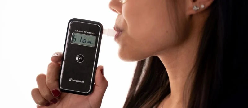 A lady blowing into Andatech AlcoSense Stealth personal breathalyser