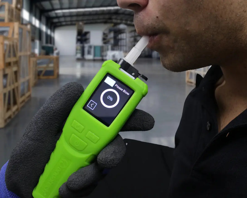 Person blowing into the Andatech Vanguard professional breathalyser to take an alcohol breath test in an indoor setting